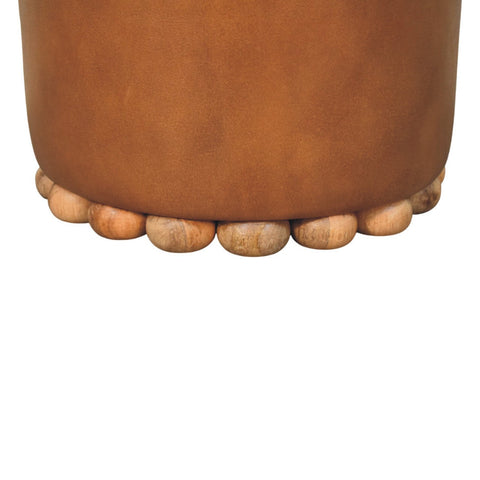 Tan leather bola leather stool with cylindrical shape and scalloped base of rounded wooden beads