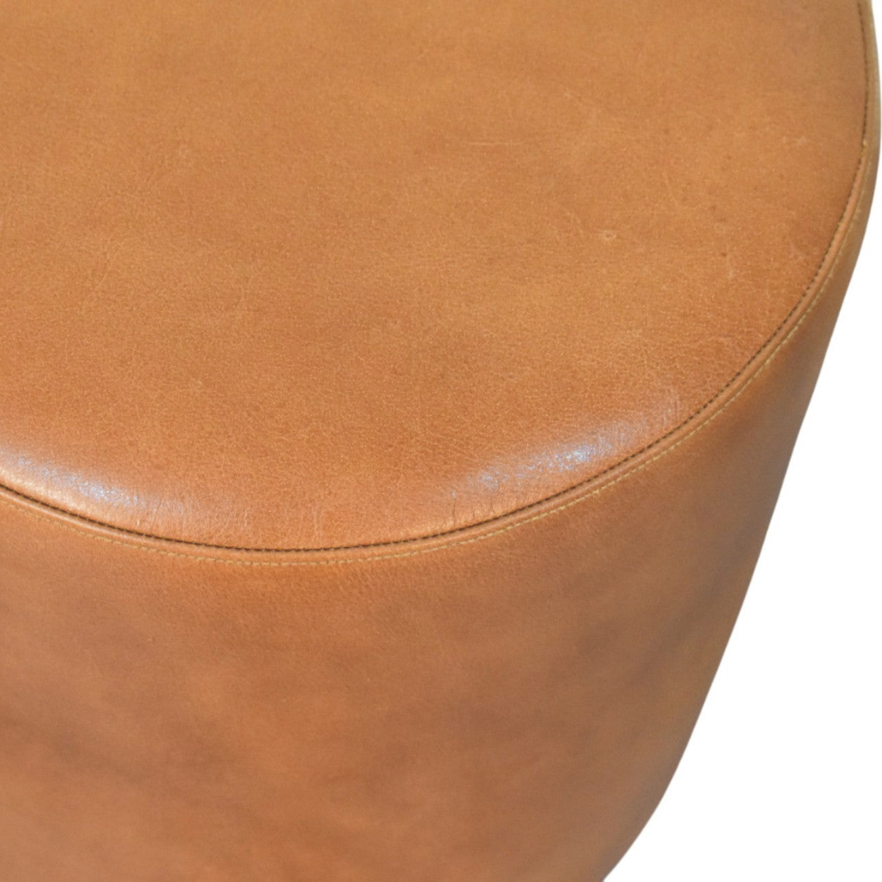 Tan leather bola leather stool with smooth rounded top and visible stitching along the edge