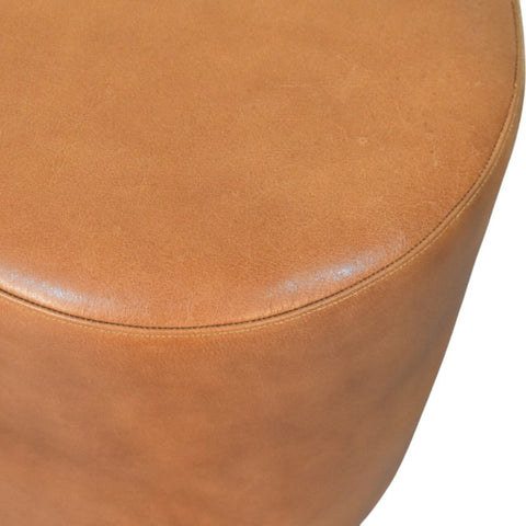 Tan leather bola leather stool with smooth rounded top and visible stitching along the edge