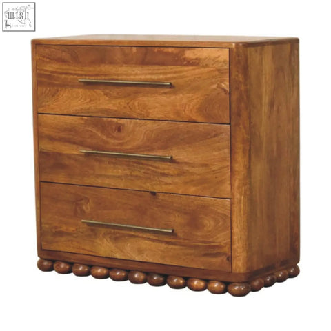 Bola three drawer chest made of rustic wood with metal handles and rounded bead detailing along the base