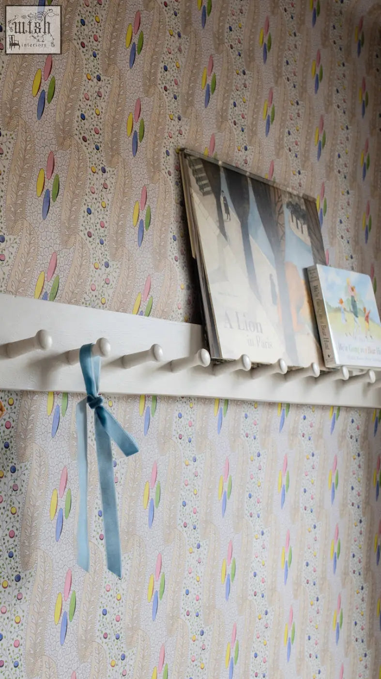 White wooden shelf with pegs and light blue ribbon showcasing bonbon textile design for digital printing wallpaper