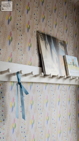 White wooden shelf with pegs and light blue ribbon showcasing bonbon textile design for digital printing wallpaper