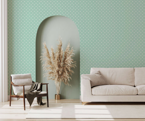 Beige upholstered bonbon sofa with clean lines and matching cushions against a polka dot wallpaper background