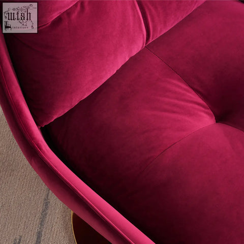 A plush deep magenta velvet bonnet swivel lounge chair with tufted cushions and a sleek curved frame