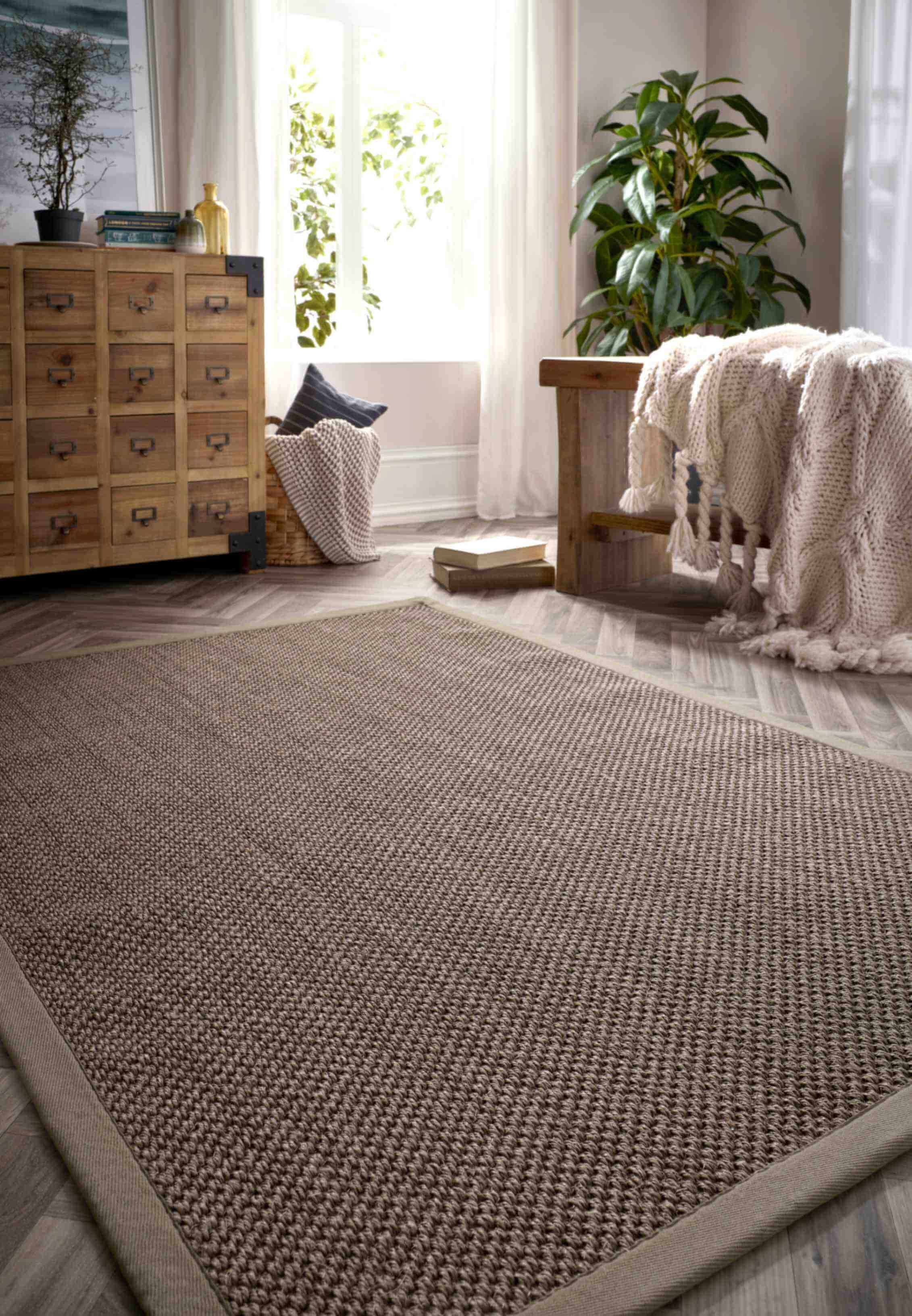 Beige woven jute rug with a textured braided pattern and a matching bordered sage green non-slip sisal design