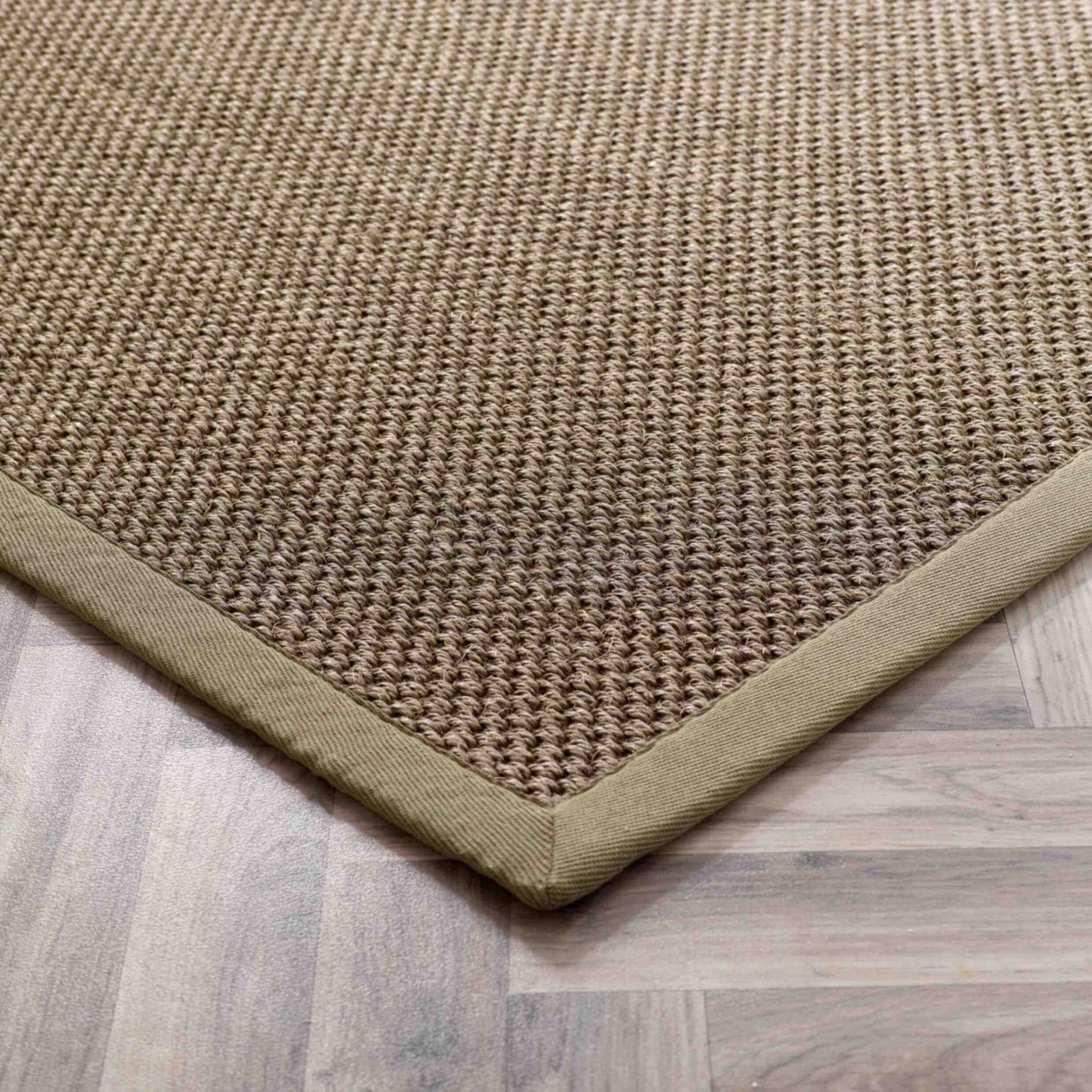 Natural fiber bordered sage green sisal rug with textured woven surface in earthy beige and olive green tones
