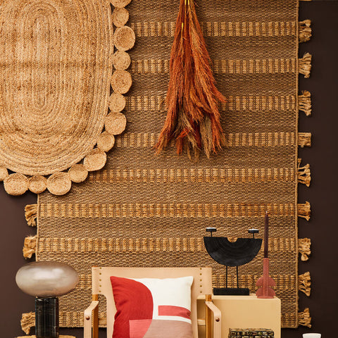 A beige wooden chair with a red white pillow on a demir ova jute rug with natural texture