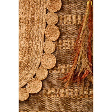 Natural fiber demir ova jute rug with woven texture and circular tassels along the edge in neutral tones