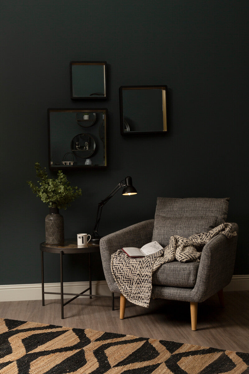 Gray textured armchair with wooden legs and a patterned throw on bosie hemp large rug in natural tones