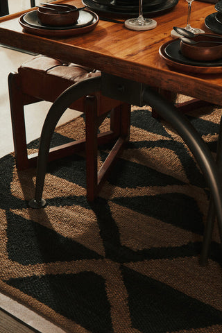 Rustic wooden dining table with dark metal legs on a bosie hemp large rug with natural wood finish and hemp large texture