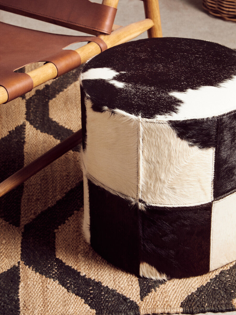 Black and white cowhide patchwork ottoman styled with bosie hemp small rug for a natural small rug look