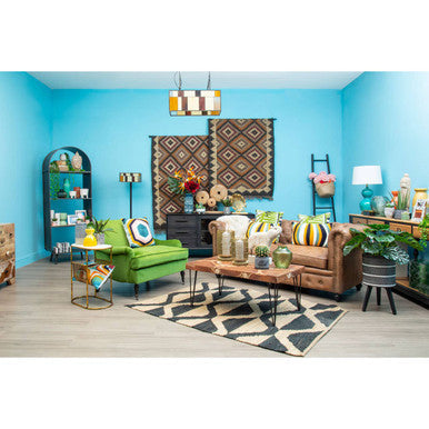 Green upholstered sofa with circular cushions and gold legs on a bosie hemp small rug in natural tones