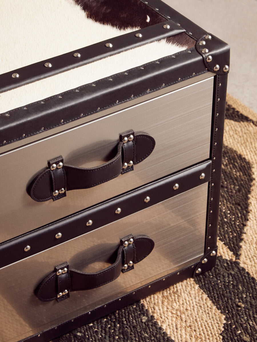 A sleek two-drawer metal chest with black leather trim and silver rivets perfect for storing hemp small rugs
