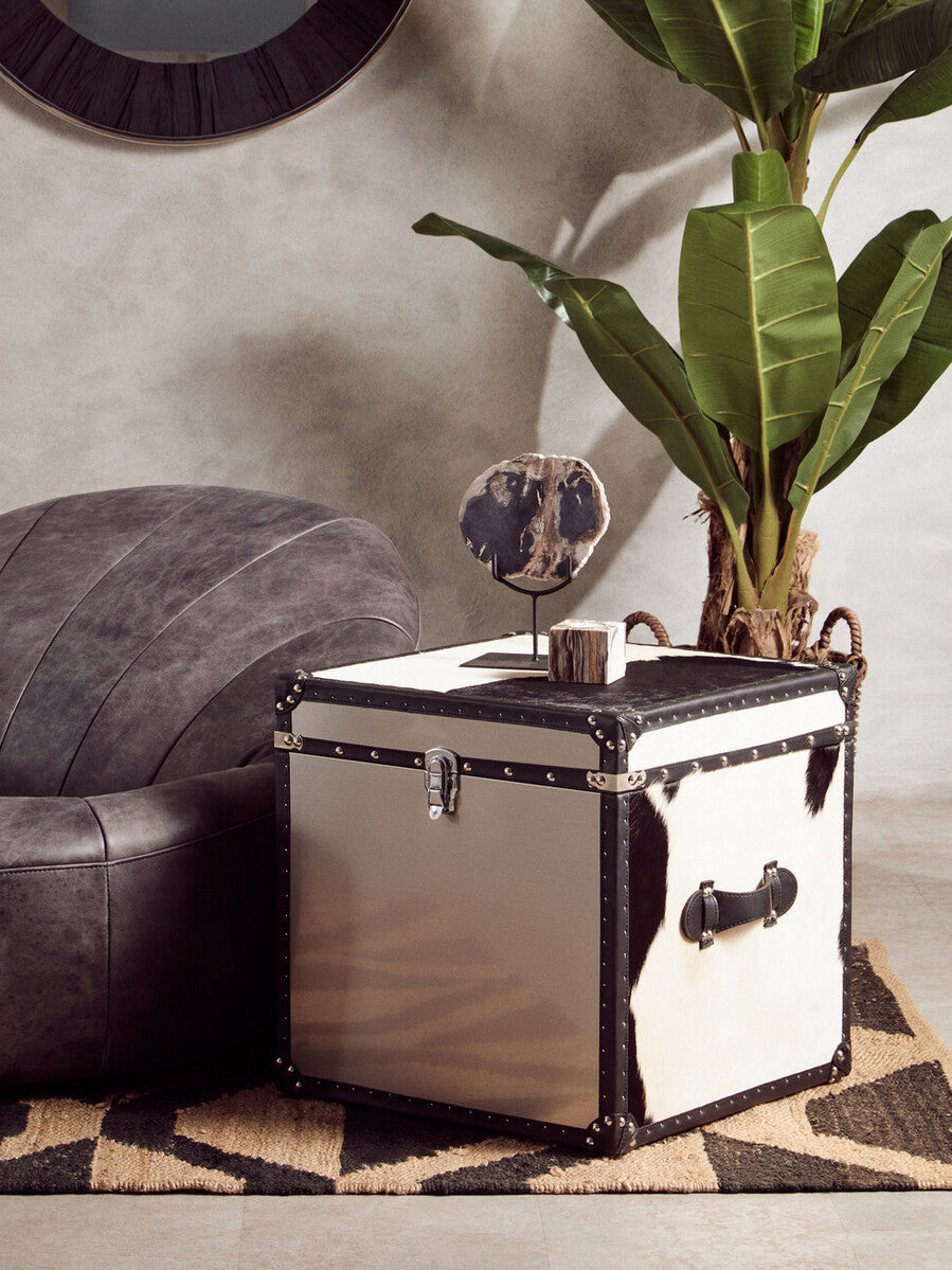 A sleek white and black leather-trimmed trunk with silver hardware perfect for storing your bosie hemp small rug