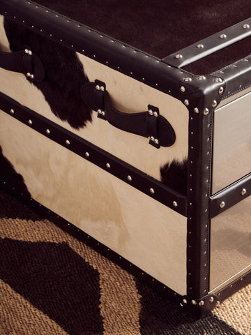 A stylish bosie hemp small rug with a rectangular trunk design, black and cream cowhide, dark leather trim, and silver rivets