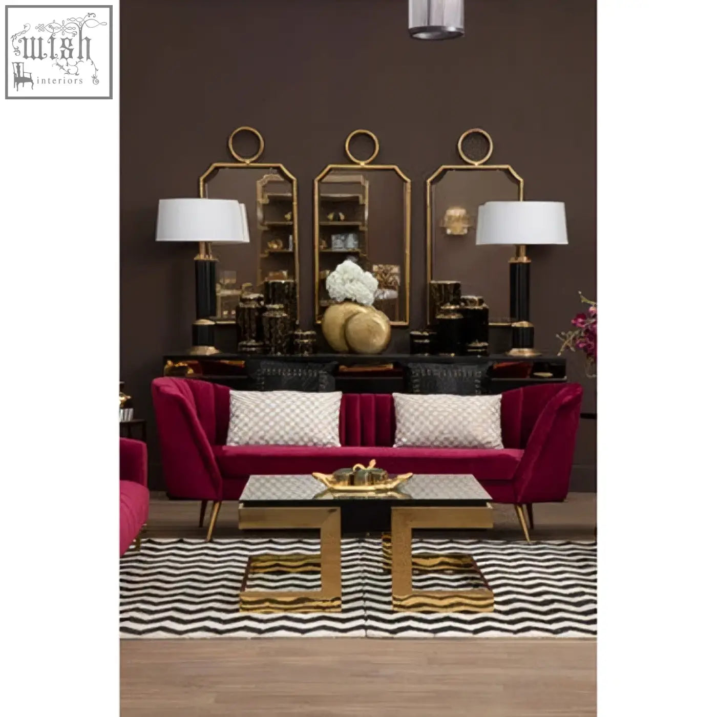 A plush burgundy velvet sofa with cream gold cushion featuring town house cream and gold check pattern and gold tone legs