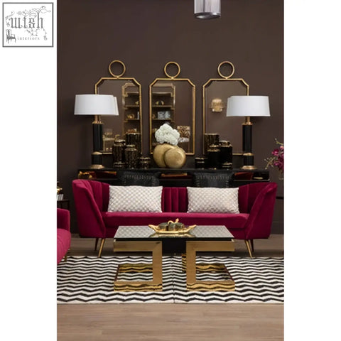 A plush burgundy velvet sofa with cream gold cushion featuring town house cream and gold check pattern and gold tone legs