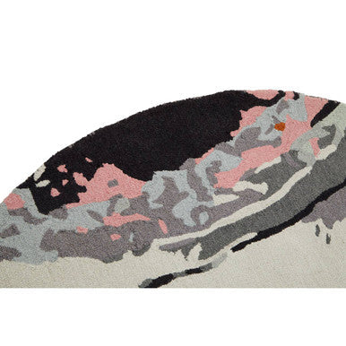 A soft textured bosie moyo round rug with a stylized wave design in black pink and gray tones