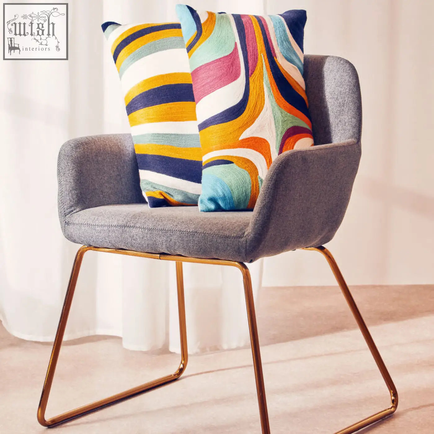 Gray upholstered armchair with gold legs and bosie ozella colorful abstract design cushions on the seat