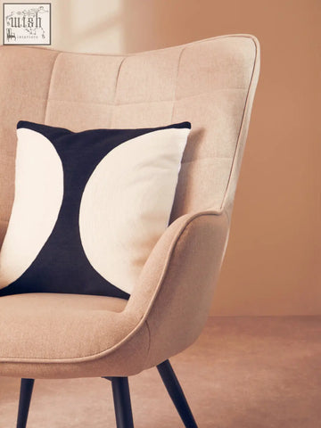 Beige upholstered armchair with black legs and a bosie ozella black and white semi circular design cushion on seat