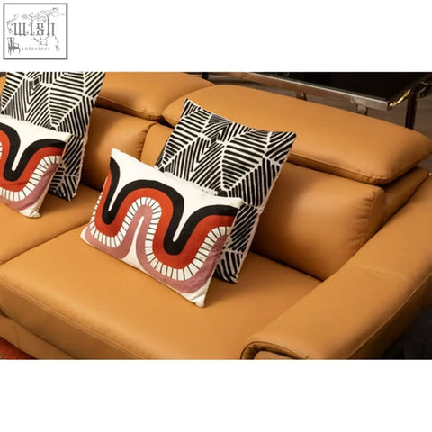 Two bosie ozella black and white square embroidered cushions with bold wave patterns on a tan leather sofa
