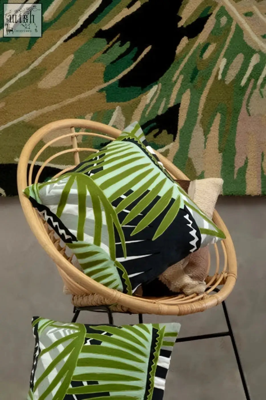 Bosie Ozella botanical green cushion with green and black palm leaf pattern on a woven wicker chair