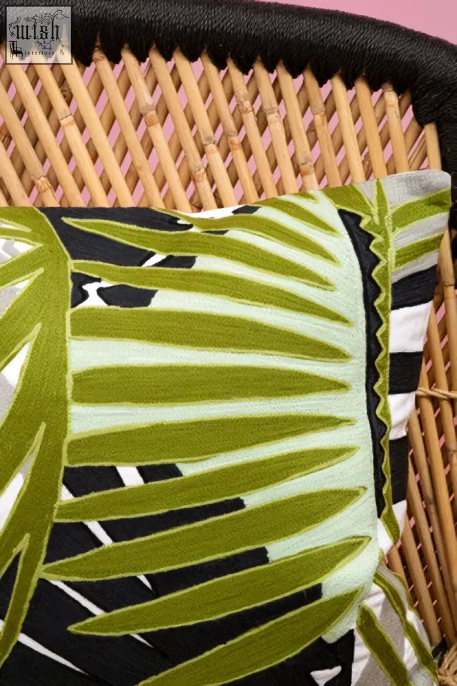 Bosie ozella botanical green cushion with vibrant green and black tropical leaf pattern on a woven wicker frame