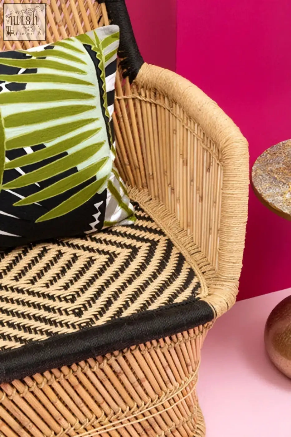 Wicker chair with woven tan frame black trim and bosie ozella botanical green cushion with geometric pattern