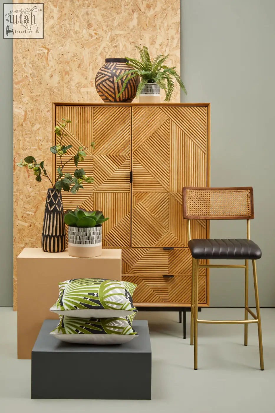 Woven rattan cabinet with geometric pattern and gold-tone hardware displayed with bosie ozella botanical green cushion