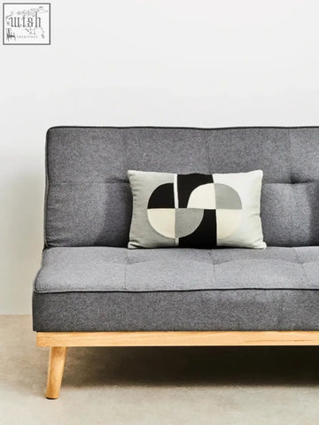Gray tufted sofa with light wood legs and a bosie ozella circular print embroidered rectangular cushion