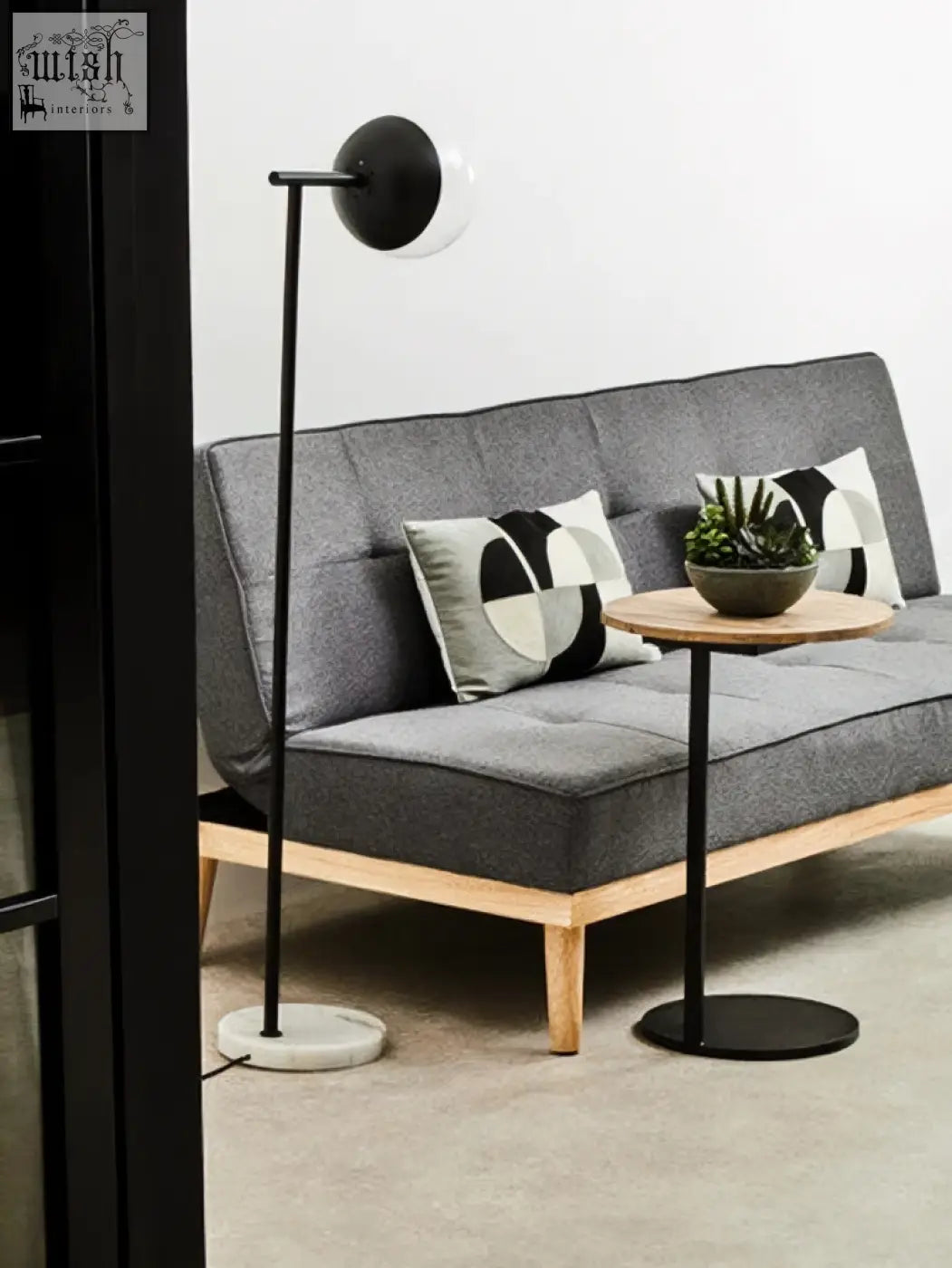 Modern black floor lamp with circular glass shade and marble base next to bosie ozella circular embroidered cushion