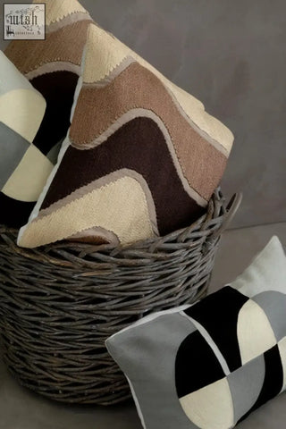 Woven wicker basket filled with bosie ozella circular embroidered rectangular cushions in earthy tones