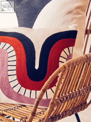 Cream-colored bosie ozella curve pattern rectangular cushion with bold red navy and pink abstract embroidered arcs and black lines