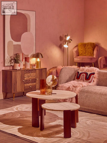A pair of nested round coffee tables with light marble tops and dark wooden legs next to an ozella curve pattern rectangular cushion