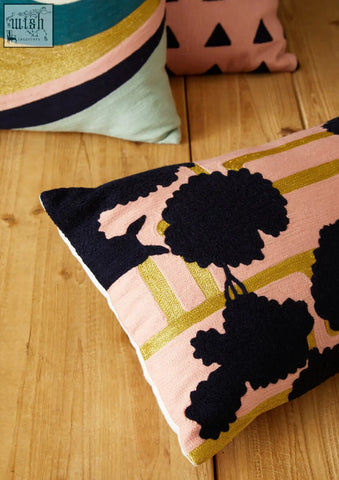 A bosie ozella curved stripes cushion with a pink base black floral embroidery and gold geometric accents