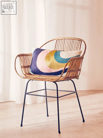 Woven rattan chair with black metal legs featuring a bosie ozella curved stripes cushion in bright colors