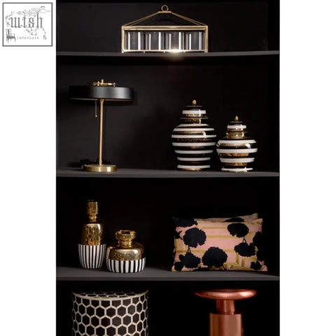 Black and white striped ceramic jars with gold accents complement the bosie ozella floral design cushion for stylish decor