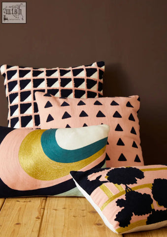 A collection of four bosie ozella floral design cushions with bold geometric patterns in pink black gold teal and cream