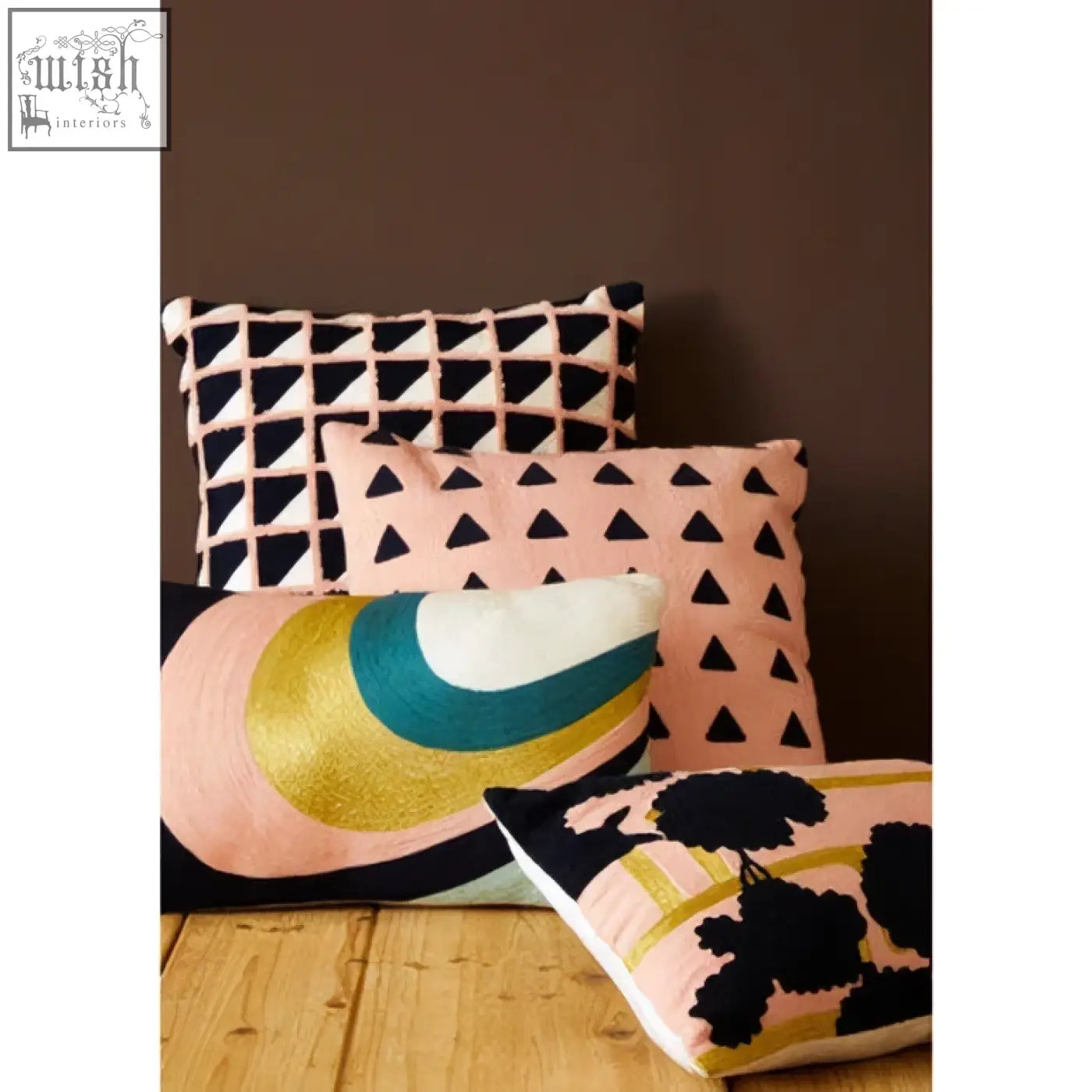 A soft pink bosie ozella floral design cushion with bold black floral pattern and gold trim design cushion