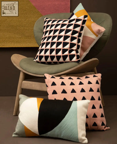 Three decorative bosie ozella multi colour rectangular cushions with geometric triangle patterns in pink black and teal