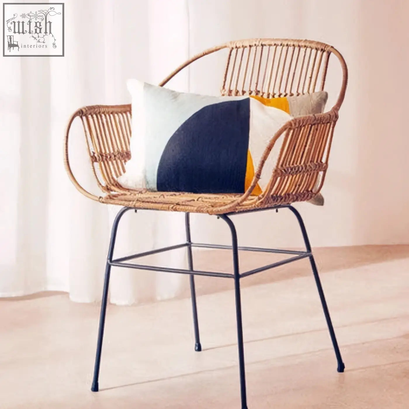 Woven rattan armchair with black metal legs featuring an ozella multi colour rectangular cushion with geometric print
