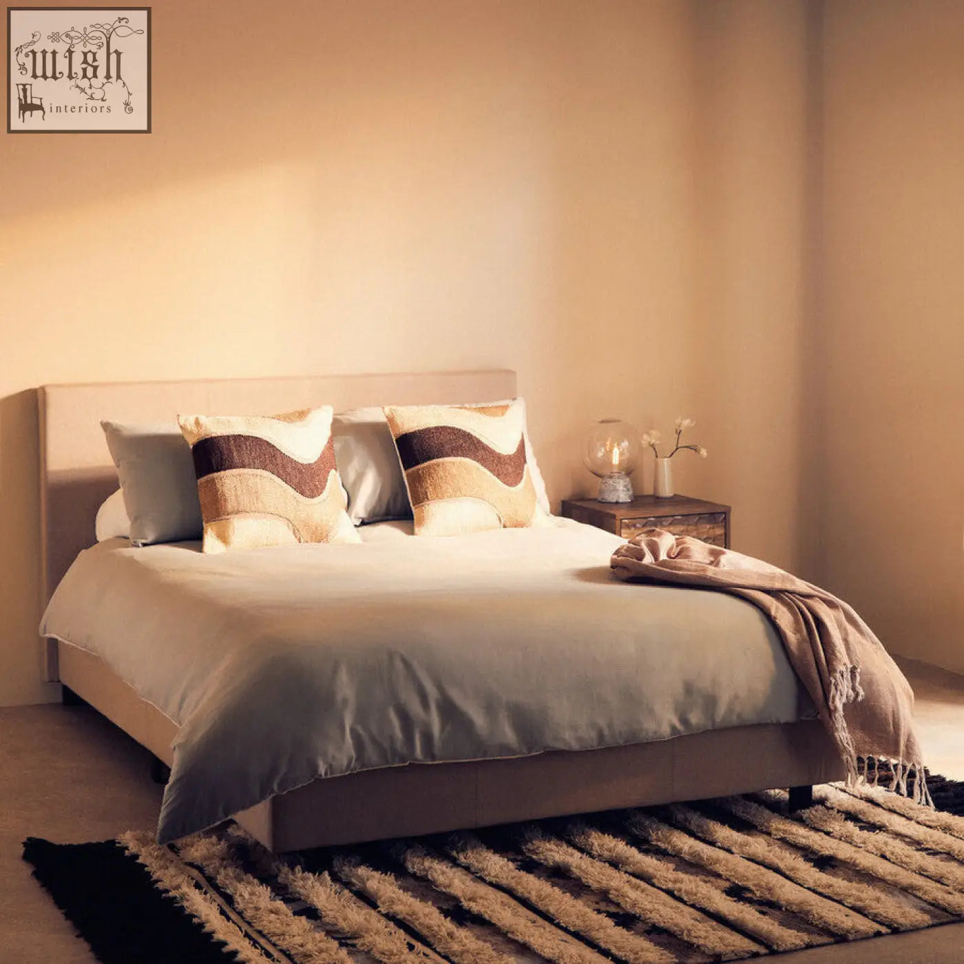 Beige upholstered bed with sleek modern design and bosie ozella natural tonal cushion in brown and cream patterns