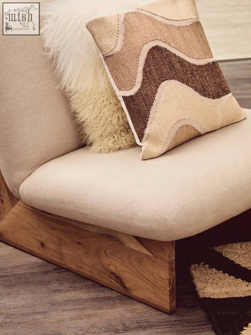 Beige bosie ozella natural tonal cushion with wavy brown and cream embroidery on a wooden armchair