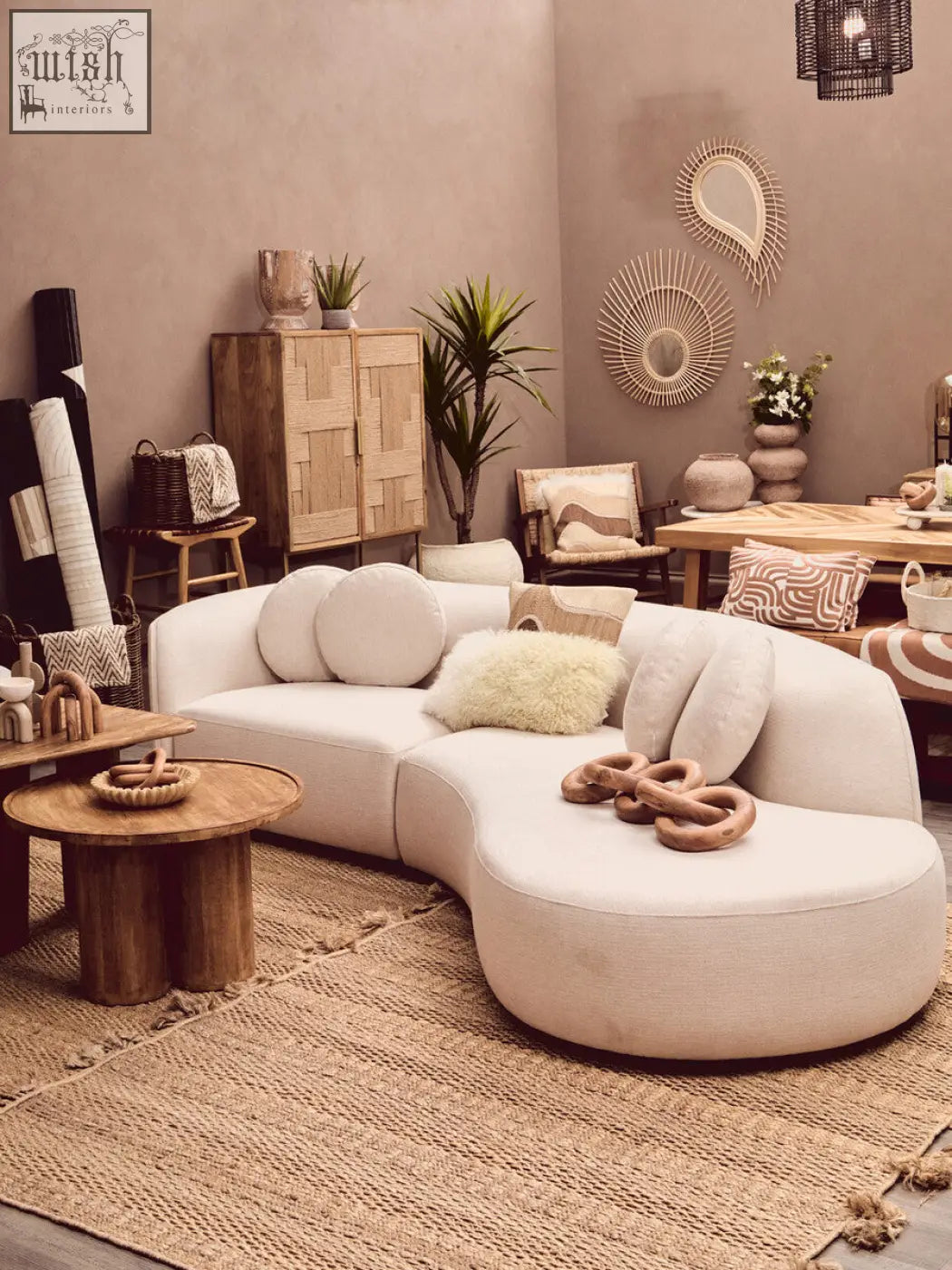 Cream-colored curved sectional sofa with soft upholstery and natural tonal cushions by bosie ozella natural tonal cushion