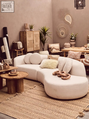 Cream-colored curved sectional sofa with soft upholstery and natural tonal cushions by bosie ozella natural tonal cushion