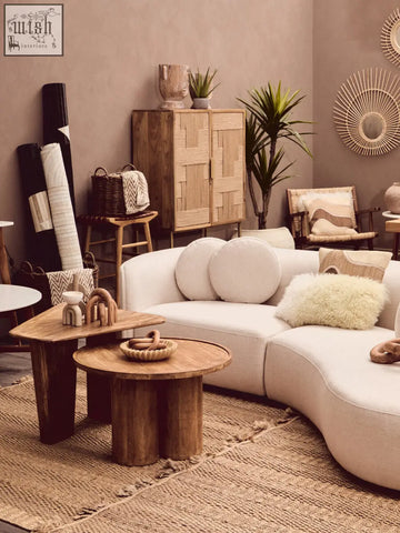 Cream-colored curved sectional sofa with bosie ozella natural tonal cushion and fluffy off-white throw pillow