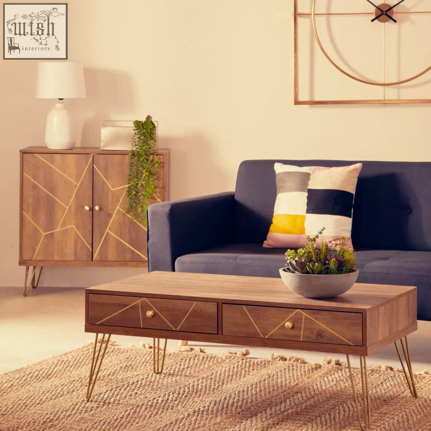 Modern wooden coffee table with gold geometric inlays and slender metal legs next to bosie ozella patch design cushion