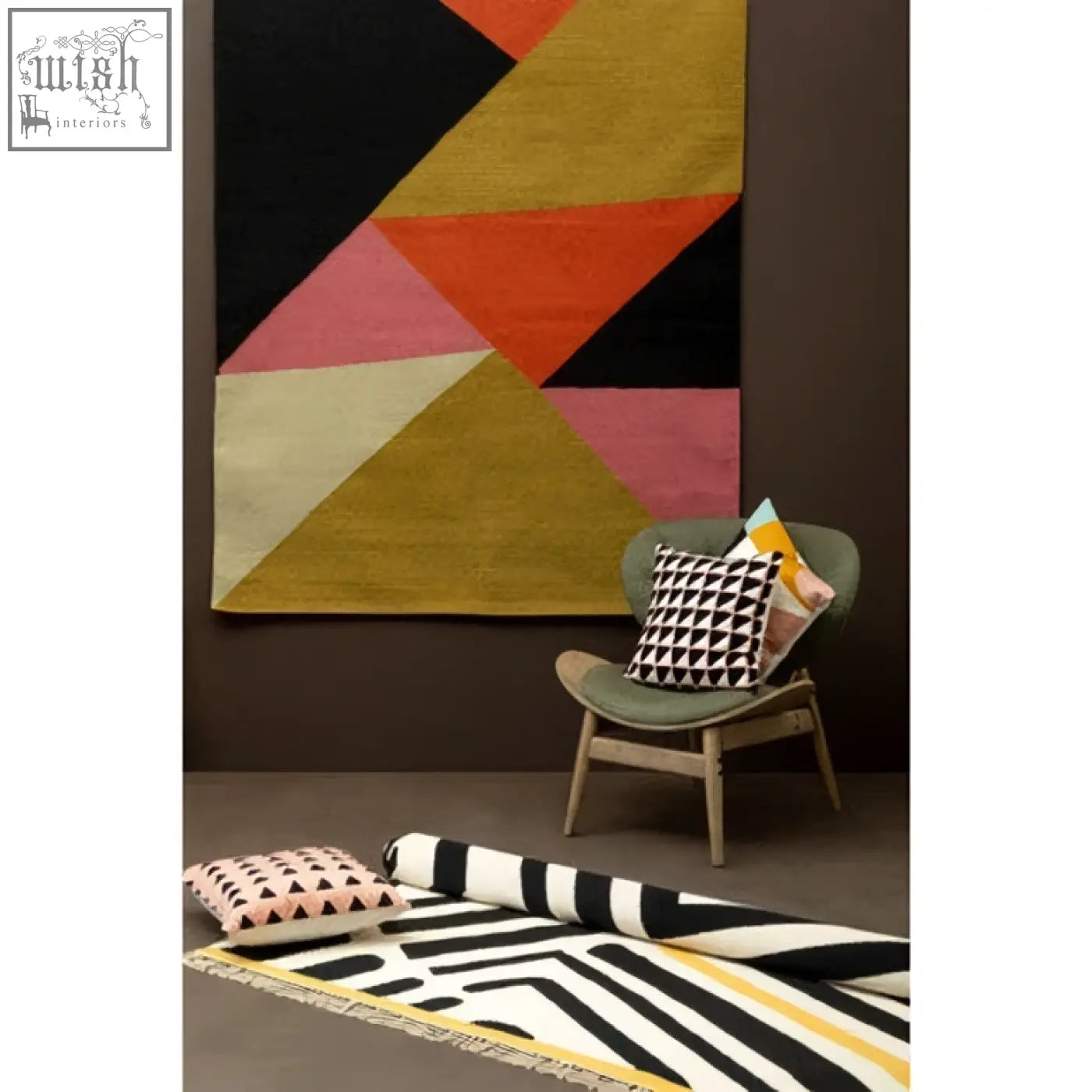 Bosie ozella pink cushion on a geometric-patterned rug with bold black orange pink and mustard yellow triangles