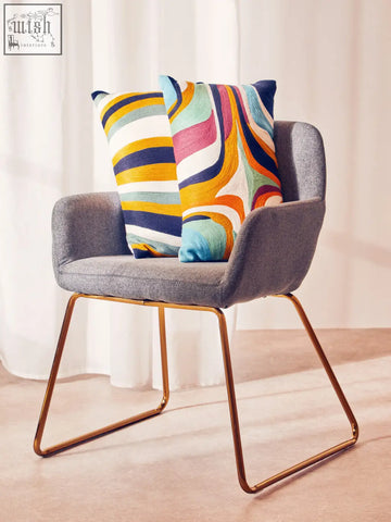 Gray upholstered armchair with gold metal legs and bosie ozella stripes design cushion in colorful abstract print