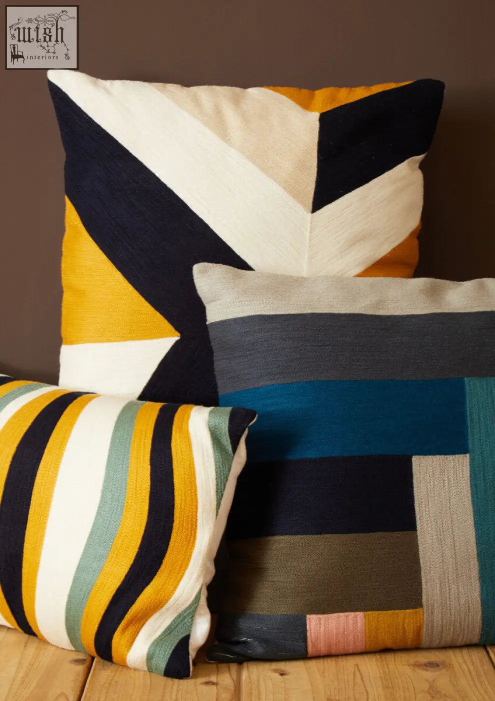 Three bosie ozella stripes design cushions with bold geometric patterns in navy mustard yellow cream teal and olive green